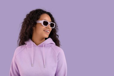 Mor arka planda güneş gözlüklü güzel Afro-Amerikan kadın portresi