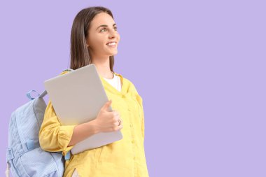 Sırt çantası ve dizüstü bilgisayarı leylak arkaplanda olan bir kız öğrenci.