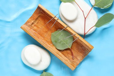 Mavi arka planda akupunktur iğneleri ve spa taşlarıyla bambu standı