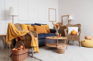 Sonbahar dekoru, kanepesi ve hasır koltukları olan bir oturma odası.