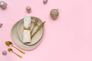 Pembe arka planda Noel topları olan güzel bir masa.