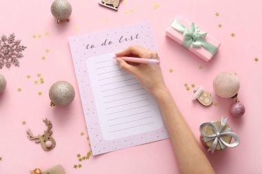 Pembe arka planda Noel dekoru olan kadın yapılacaklar listesi yazıyor