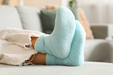 Sıcak mavi çoraplı bir kadın evdeki kanepede oturuyor, yakın plan.