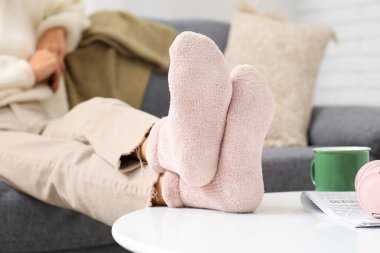Sıcak pembe çoraplı bir kadın evdeki kanepede oturuyor.
