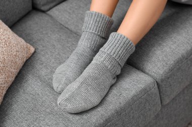 Gri örgü çoraplı kadın evdeki kanepede oturuyor, yakın plan.