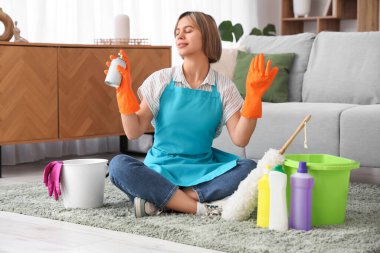 Hava spreyi ve temizlik malzemeleriyle evde oturan güzel genç bir kadın.