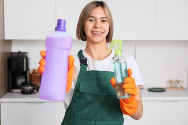 Mutfakta temizlik malzemeleriyle güzel genç bir kadın.