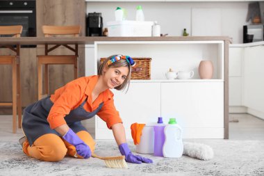 Mutfakta fırça ve deterjan şişeleriyle güzel genç bir kadın var.