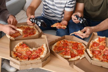 Pepperoni pizzalı erkek arkadaşlar evde video oyunu oynuyor, yakın plan.