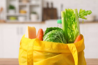 Mutfakta farklı taze ürünler bulunan sarı alışveriş torbası.