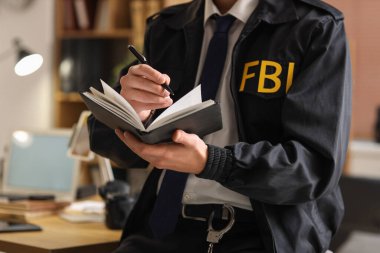 Erkek FBI ajanı ofiste deftere yazıyor, yakın plan.