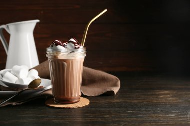 Ahşap zemin üzerinde lokum olan bir bardak çikolatalı süt.