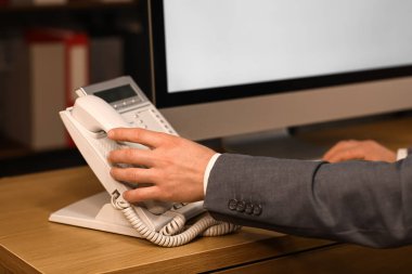 Bilgisayarlı genç bir işadamı gece ofiste telefon alıyor, kapatıyor.