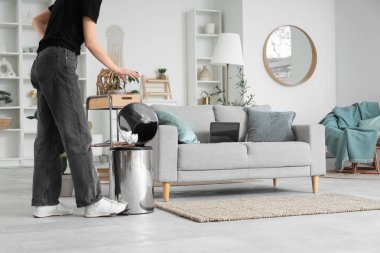 Evdeki çöp kutusuna buruşmuş kağıt atan kadın.