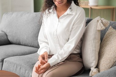 Evdeki kanepede oturan şık beyaz gömlekli güzel Afro-Amerikalı kadın.