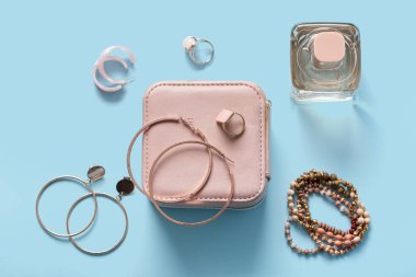 Güzel mücevherleri ve mavi arka planda bir şişe parfümü olan bir organizatör.