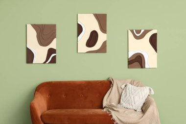 Konforlu kanepe ve yeşil duvarda resimler.