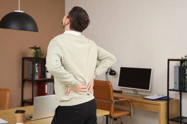 Ofiste sırt ağrısı çeken genç bir adam.