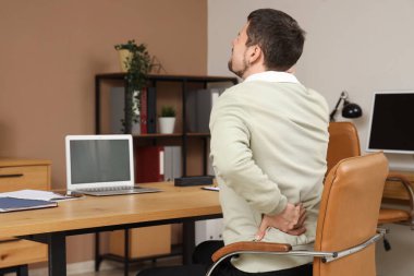 Masada sırt ağrısı çeken genç bir adam var.