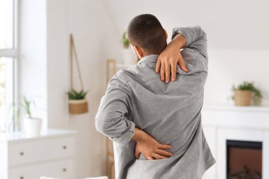 Evde sırt ağrısı çeken genç bir adam.