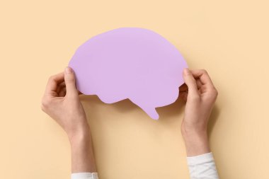 Sarı arka planda kağıt insan beyni olan kadın eller.