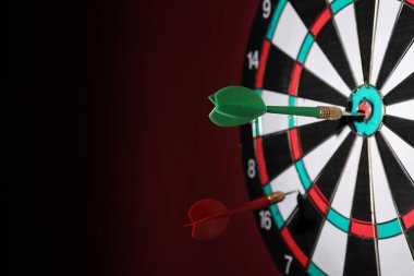 Koyu kırmızı duvarda dartları olan dart tahtası