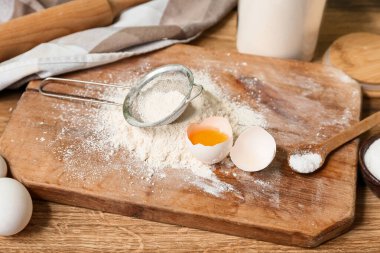 Tahta un, taze yumurta ve ahşap masada elek.