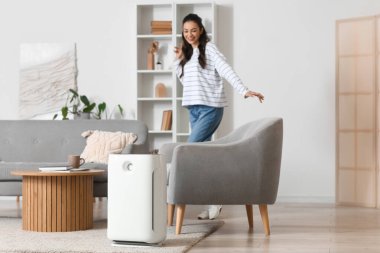 Evdeki genç bayana karşı halının üzerinde modern hava temizleyicisi