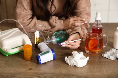 Mutfaktaki masada termometresi olan hasta genç bir kadın.