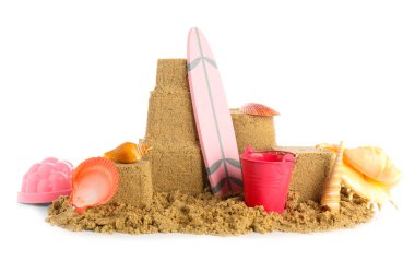 Beyaz arka planda kumdan, deniz kabuklarından, mini sörf tahtası ve kovadan yapılmış bir kale.