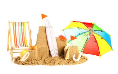 Kumdan, deniz kabuklarından, küçük şemsiyelerden, güverte sandalyesinden ve beyaz arka planda sörf tahtasından kaleler.