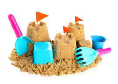 Beyaz arka planda kumdan ve plaj oyuncaklarından yapılmış bir kale.
