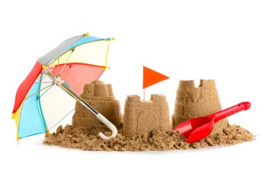 Beyaz arka planda kumdan kale, oyuncak kürek ve küçük şemsiye