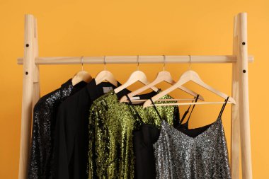 Soyunma odasındaki sarı duvarın yanında gece elbiseleriyle dizilin. Yakın çekim.