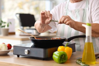 Son sınıf öğrencisi kadın mutfaktaki kızarmış yiyeceklere biberiye ekliyor, yakın plan.