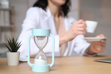 İş kadınına karşı masadaki kum saati ofiste kahve içiyor, kapatıyor.