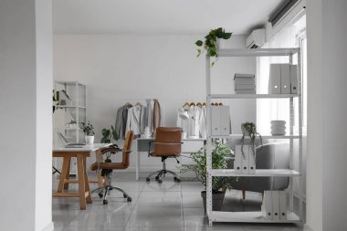 İş yeri, ev bitkileri ve raflarda şık giysileri olan giyim mağazasının içi.