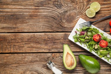 Çeri domatesli lezzetli avokado salatası ve ahşap arka planda limon dilimleri.