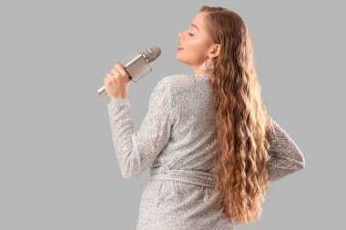 Mikrofonlu güzel bir kadın arka planda karaoke söylüyor.
