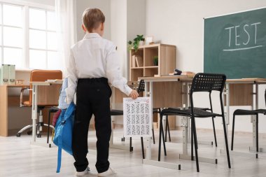 Sınav sonuçları ve sırt çantası olan tatlı bir okul çocuğu. Sınıfta, arka planda.