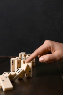 Siyah ahşap masada domino efektini durduran kadın