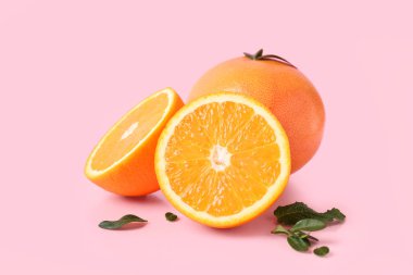 Pembe arka planda yapraklı portakal ve greyfurt kes