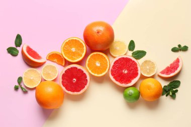 Renk arkaplanında nane yapraklı farklı kesim narenciye meyveleri