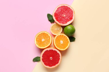 Renk arkaplanında nane yapraklı farklı kesim narenciye meyveleri