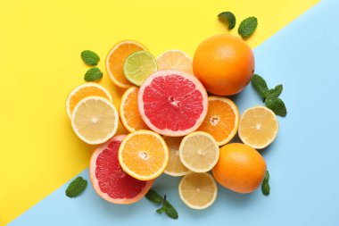 Renk arkaplanında nane yapraklı farklı kesim narenciye meyveleri