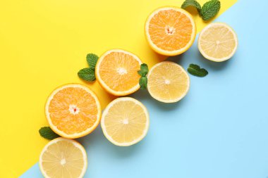 Renk arkaplanında nane yapraklarıyla portakal ve limon kes