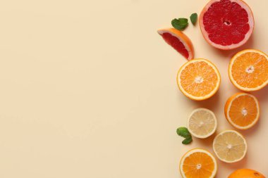 Farklı kesilmiş turunçgil meyveleri ve bej arkaplanda nane yaprakları