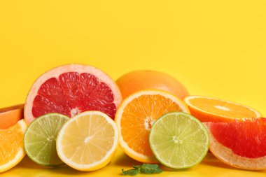 Sarı arka planda farklı kesilmiş narenciye ve nane yaprakları.