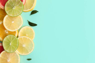 Turkuaz arka planda farklı turunçgil dilimleri ve yapraklar