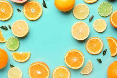 Turkuaz arka planda farklı kesilmiş turunçgil meyveleri ve yapraklardan yapılmış çerçeve